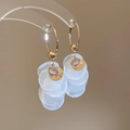 Detail of gold hoop earrings featuring white shell discs and a pink sunburst gemstone charm - Gold White Sun Style