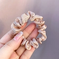 Detailed close-up of champagne silk satin hair scrunchie with soft pleated texture - Lotus root pink