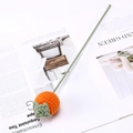 Close-up of hand-knitted orange persimmon flower with green stem on a white magazine background - Persimmon Branch