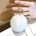White fluffy plush pompom keychain with golden metal clasp shown on hand - Small White Pom Pom