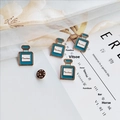 Spille a forma di flacone di profumo in smalto blu con scritta Flawless su tessuto minimalista - Boccetta di profumo