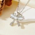 Détail macro du collier nœud argenté avec pierres œil de chat blanches et perle centrale - Style Nœud Pierre Blanche Argent Double Diamant (T015)