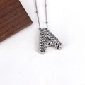 Macro shot of silver letter A pendant with unique 3D pyramid texture on white linen - Letter A