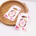 Floral plastic gift bags with Live and Let Live quote on a rustic woven tray - No. 96 (Flower & Feather)