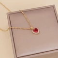 Elegant gold necklace with red heart gemstone and zircon halo on champagne box - Red