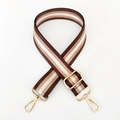 Macro detail of striped nylon bag strap with gold glitter threads and metal clips - Brown