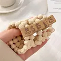 Cream-colored bubbly textured elastic hair tie featuring a cute brown rabbit suede patch - Knit With Rabbit Tag / White Rabbit