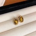 Close-up detail of retro geometric gold earrings with amber tiger eye stones in jewelry box - Oval (HE17390)