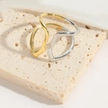 Close-up of minimalist gold and silver face outline rings on a beige stone surface - Abstract Face Circular Style