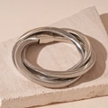 Macro-opname van een zilveren meerlaagse slangenarmband op beige stenen achtergrond - Zilver