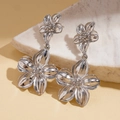 Detail view of silver floral earrings with brushed metallic texture on white marble base - Silver Double Flower Dangle