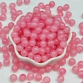 Close-up of translucent pink round glass beads in a white flower-shaped ceramic dish - 4mm / Neon Pink