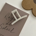 Dettaglio di un mollettone rettangolare in acetato bianco perlato sopra un libro decorativo - Pinza in Lega a T con Base Argento