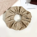 Close-up of khaki faux leather scrunchie with pleated texture and soft glossy finish - Brown