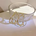 Elegante gouden gedraaide creolen met gehamerde textuur op glazen rand gepresenteerd - 4cm / Dubbele Lus Gekruiste Gehamerde Stijl / Goud / 925 zilveren naald