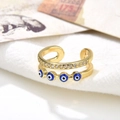 Macro shot of double-layered gold ring with blue evil eye charms and inlaid cubic zirconia - Blue Eyes Style