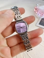 Close-up of a purple square dial ladies watch with silver metal strap held by hand - Silver Band Purple Dial