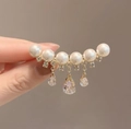 Elegant gold brooch with white pearls and sparkling rhinestone tassels held in hand - Pearl Tassel Pendant