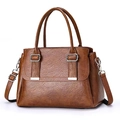 Close-up of brown litchi pattern PU leather handbag with metallic buckle and twin handles - Earthy Yellow