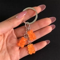 Detailed view of three orange resin gummy bear charms on a metallic keychain - Orange