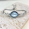 Silver oval watch with crystal leaf bracelet displayed on textured beige stone - Silver Oval
