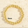 Detailed macro view of 8mm polished gold bead stretch bracelet on stone surface - 8mm