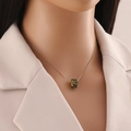 Gros plan détaillé du collier en acier inoxydable doré avec pendentif en zircon vert - Vert
