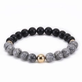 Close-up of matte black beads with white marble stone and a gold-tone accent bead - Map Stone