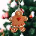 Close-up of a gingerbread girl resin ornament with a red bow on a green Christmas tree - Red Heart Style