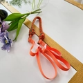 Detail of vibrant orange nylon braided pet leash with green accents on white surface - Orange and Green Spotted Shoulder Strap