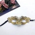 Close-up of golden lace masquerade mask showing intricate embroidery and black ribbon ties - Fire Phoenix