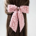 Dettaglio ravvicinato di una clip per capelli rosa con fiocco, perle e pietre preziose - Rosa