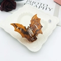 Detailed view of amber acetate bat hair claw clip on decorative vintage plate - Caramel Ink Texture