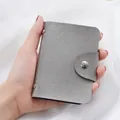 Silver cross-grain card holder with 24 slots and snap closure held by hand - Silver - Saffiano Grain / 8-card Single-sided Card Slot