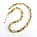 Polierte Goldperlenkette mit verstellbarem Karabinerverschluss auf weißem Grund - 7mm