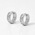 Close-up of silver stainless steel huggie hoop earrings with zircon star pattern - Silver