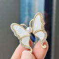 Broche papillon vintage dorée avec émail blanc et une pierre précieuse bleu marine - Papillon en Cristal Bleu