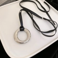 Close-up of minimalist silver round pendant necklace with black leather cord on a tray - 10# Necklace-Silver-Ring