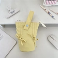 Macro shot of pale yellow fabric pencil case with decorative bow and handle on workspace - Yellow