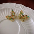 Macro shot of gold butterfly earrings with colorful zircons on a white embossed plate - Multicolor Butterfly Stud Earrings