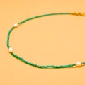 Close-up of green crystal faceted beads and white pearls on golden titanium steel necklace - GX03008B (Emerald Beads with 3 Pearls)