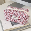 Detailed macro of floral quilted fabric pouch with zipper and brand label on art books - Dark Red Floral
