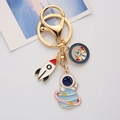 Golden astronaut keychain with enamel rocket and planet charms on white background - Astronaut Holding Ball / Single OPP Bag Packaging