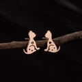 Macro detail of rose gold cat stud earrings with heart and star cutouts on a branch - Rose Gold