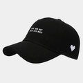 Close-up of black cotton baseball cap with white heart embroidery and side text detail - Adjustable / Black