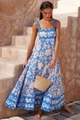 Detailed close-up of blue floral maxi dress with wavy straps and bohemian straw bag - Light Blue Print