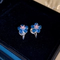 Dettaglio di orecchini a clip a fiore blu con perle su velluto nero - Orecchini a clip a forma di fiore blu
