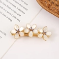 Detail of gold flower hair clip with white petals and purple crystals on a book - Style 9 Large Three Flowers with Purple Rhinestone