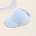 Détail d'une visière bleu clair pour enfant avec nœud rose brodé et bord incurvé - Style Noeud-Bleu