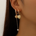 Detail of asymmetric gold earrings with shell, pearl, and heart charms on a model - KC Gold Shell Heart Style (10720)